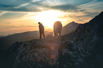 Silueta de una persona con su perro en la montaña al atardecer