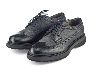 Beautiful pair of demi-season men's leather shoes with perforations and inserts of gray monochrome wool, isolated on a white background with shadow.