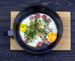 fried eggs with dill in a pan on a wooden table