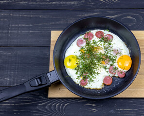 fried eggs with dill in a pan on a wooden table