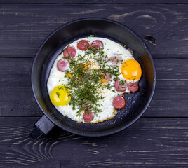fried eggs with dill in a pan on a wooden table