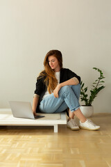 Beautiful woman working on a laptop in minimalist interior apartment