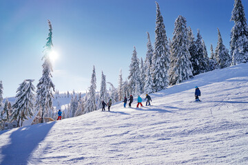 Snowy mountains and ski lifts. Skiers and snowboarders skiing downhill to village.