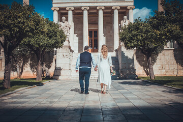 Beautiful wedding couple in Athens, Greece. Look at the classical architecture of University, the view from the back