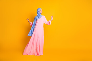 Fototapeta na wymiar Full length body size view of nice fashionable cheerful feminine muslimah walking copy space isolated on vivid yellow color background