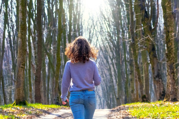 Young girl walking in the spring forest in sunny weather