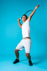 Fototapeta na wymiar Full length studio portrait of a tennis player man on blue background