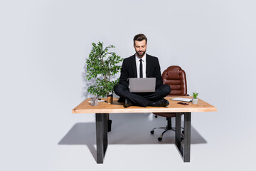 Full body photo of handsome business guy hold notebook chatting colleagues good mood sitting table lotus yoga pose wear blazer shirt pants shoes suit isolated grey background