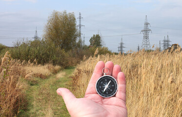 Old classic navigation compass in hand on natural background as symbol of tourism with compass,...