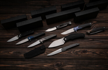 Folding knives on a wooden background. Pen knives on a dark brown back. - obrazy, fototapety, plakaty