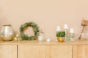 Modern interior design concept. Bright beige and golden apartment  with wreath made of fir branches, gold toys. Traditional winter holidays Christmas / New Year.