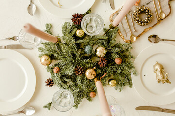 Festive christmas / Thanksgiving table decorated with fir branches, garland, candles, plates, knifes, forks. Flat lay, top view. Christmas / New Year composition. Winter holidays concept.