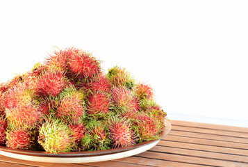 Rambutan in the food tray on the table with white wall