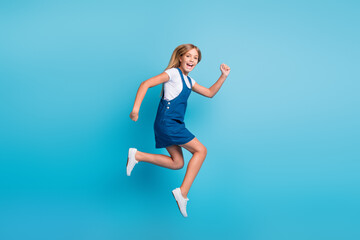Fototapeta na wymiar Full size photo of cheerful funny blond girl jumping run wear t-shirt mini dress sneakers isolated on pastel blue color background