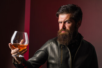 Sommelier degustates whiskey. Strong alcohol. Brutal man drinks whiskey. Degustation and tasting. Man in leather jacket drinks whiskey.