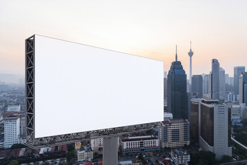 Blank white road billboard with Kuala Lumpur cityscape background at sunset. Street advertising poster, mock up, 3D rendering. Side view.