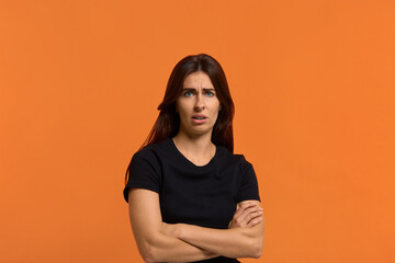 Obraz premium is it pleasant to him. Dissatisfied caucasian woman in black t-shirt disgusting expression as sees something unpleasant, keeping arms crossed and open mouth. Female isolated over an orange wall
