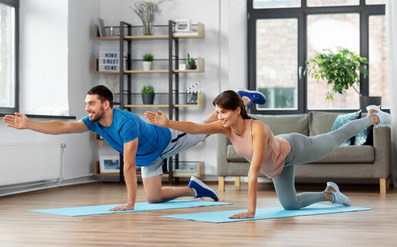 sport, fitness, lifestyle and people concept - smiling man and woman exercising at home