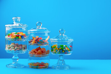 Glass containers with colorful candies against blue background