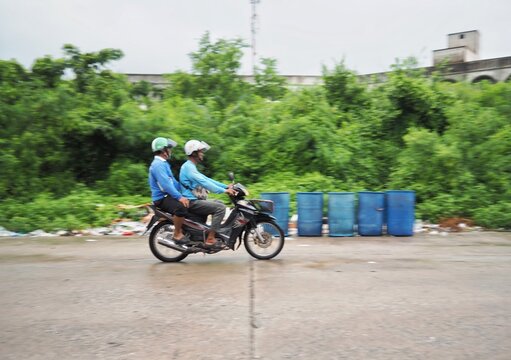 A motor bike is running on the road Through the blue trash.