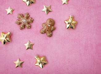 shiny golden christmas ornaments and gingerbread cookies on paper pink background