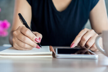 woman hand holding a pen and using smart phone for studying  online, e- learning from home concept 
