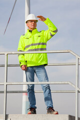 Fototapeta na wymiar Mature engineer looking out for a green future in front of a wind turbine