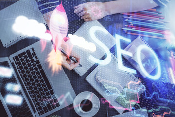 Multi exposure of woman's hands making notes with SEO icon. Concept of Search engine optimization