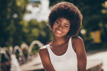 Portrait of attractive pretty dark skin girl toothy smiling in camera in summer town center park