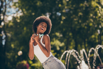 Photo of funky afro american girl with wireless headset enjoy summer town center park nature