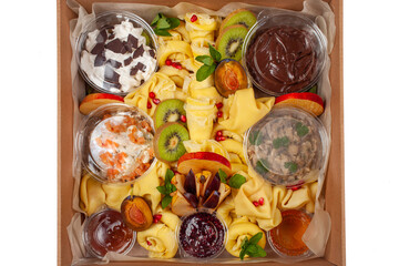 Fototapeta na wymiar Delivery of food in a box, delicious and fresh food. Convenient boxing for eating at home, at work, in nature. Beautiful pancakes with fruit, chocolate, salmon