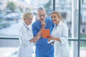 Smiling hospital team studying something on tablet, discussing