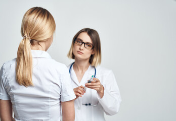 A nurse doctor in a medical gown explains something to a patient in a white T-shirt