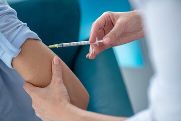 Close-up of female hands making injection into arm
