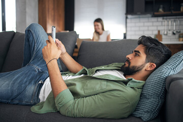 Man relaxing on sofa using mobile phone