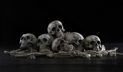 Pile of old skulls and bone put on dark background which has dim light