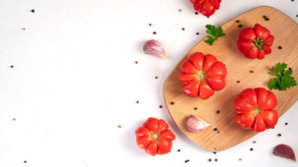 Red tomatoes with garlic and spices. Fresh vegetables on a wooden cutting board.