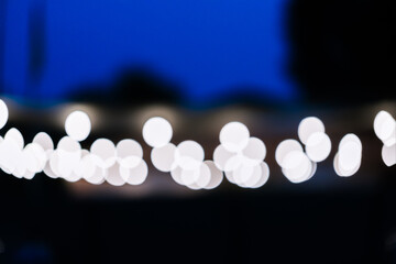 Blurred street light bulbs on black and blue evening city background