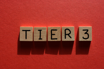 Tier 3, coronavirus alert levels, word in wooden alphabet letters isolated on red background