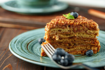Piece of honey cake with nuts on green plate