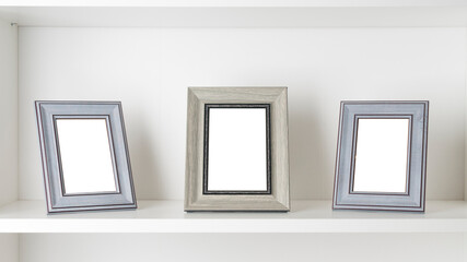 Three blank photo frames on a white shelf