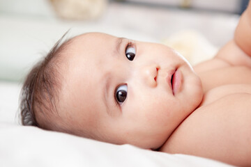 cute baby laying on the bed and looking at the camera