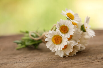 Fototapeta na wymiar Small bunch of chrysanthemum flowers tied with brown string on wooden surface with natural green bokeh background