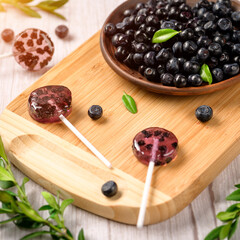Homemade lollipops made from natural dehydrated bilberry on a white wooden background. Healthy vegan vegetarian food with no sweets.