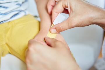 Kinderarzt klebt Pflaster auf die  Hand von Kind