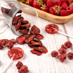 Homemade lollipops made from natural dehydrated strawberries and raspberries on a white wooden background. Healthy vegan vegetarian food with no sweets.