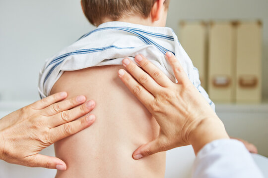 Kinderarzt oder Osteopath behandelt Rücken von Kind
