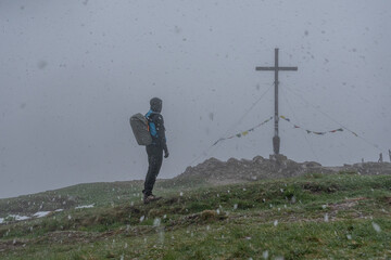 Mann am verschneiten Gipfelkreuz vom Riedberger Horn