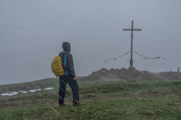 Mann am verschneiten Gipfelkreuz vom Riedberger Horn