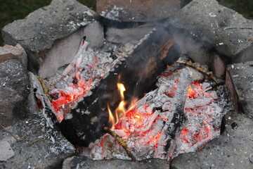 Self made campfire with embers, ashes, stones and coal as close up.